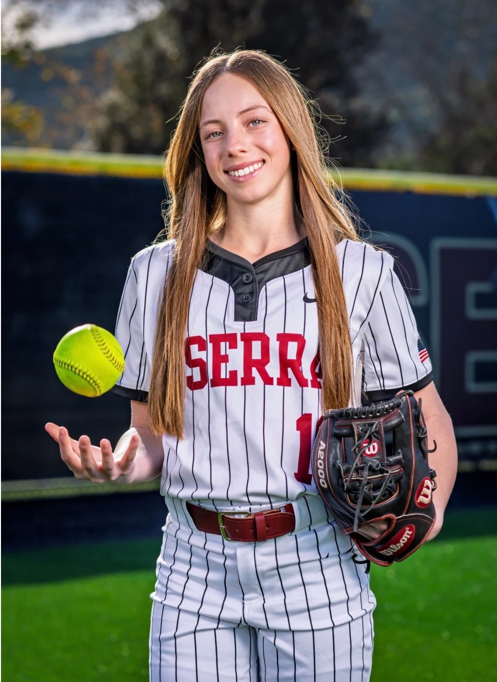 Ava Born smiling in her JSerra uniform with her glove and softball